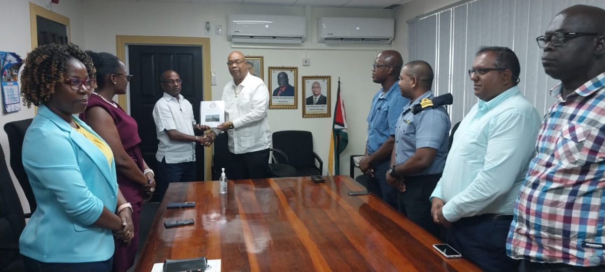 Minister of Public Works Juan Edghill (centre) receiving the report from Captain Joseph Lewis (Ministry of Public Works photo)