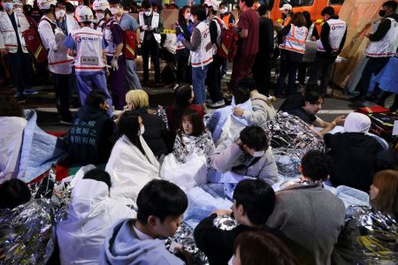 People sit on the street after being rescued, at the scene where dozens of people were injured in a stampede during a Halloween festival in Seoul, South Korea, October 29, 2022.