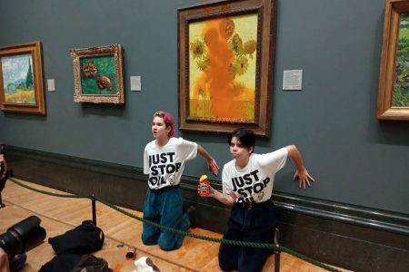 Activists of "Just Stop Oil" glue their hands to the wall after throwing soup at a van Gogh's painting "Sunflowers" at the National Gallery in London, Britain October 14, 2022. (Just Stop Oil/Handout via REUTERS)