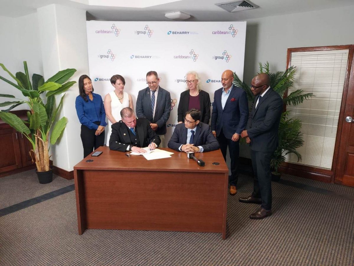 Chief Executive Officer (CEO) of XL Group, Colin Laird (seated at left) and Chairman of the Beharry Group, Anand Beharry (seated at right) signed the agreement for the joint venture. British High Commissioner Jane Miller and Canadian High Commissioner Mark Berman also witnessed the signing.