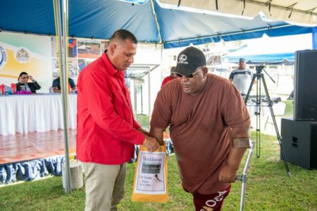 Housing and Water Minister, Collin Croal (left) holding an envelope as a house lot recipient pulls a number. (DPI photo)