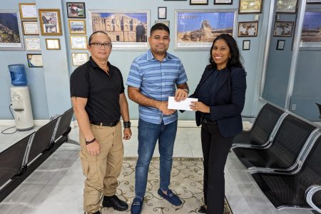 Azruddin Mohamed of Team Mohamed (centre) hands over the sponsorship cheque to Vidushi Persaud-McKinnon, Secretary-General of Archery Guyana (right) in the presence of Nicholas Hing, Head-Coach of Archery Guyana.