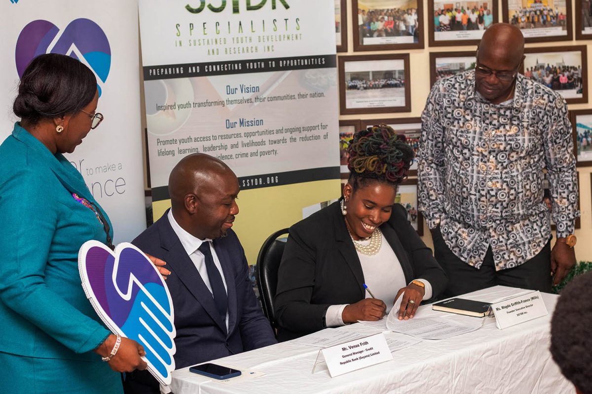 Magda Griffith-France (right), Founder/Executive Director, SSYDR signs the MOU in the presence of Venus Frith, General Manager- Credit, 
RBGL and representatives from SSYDR and RB(G)L

