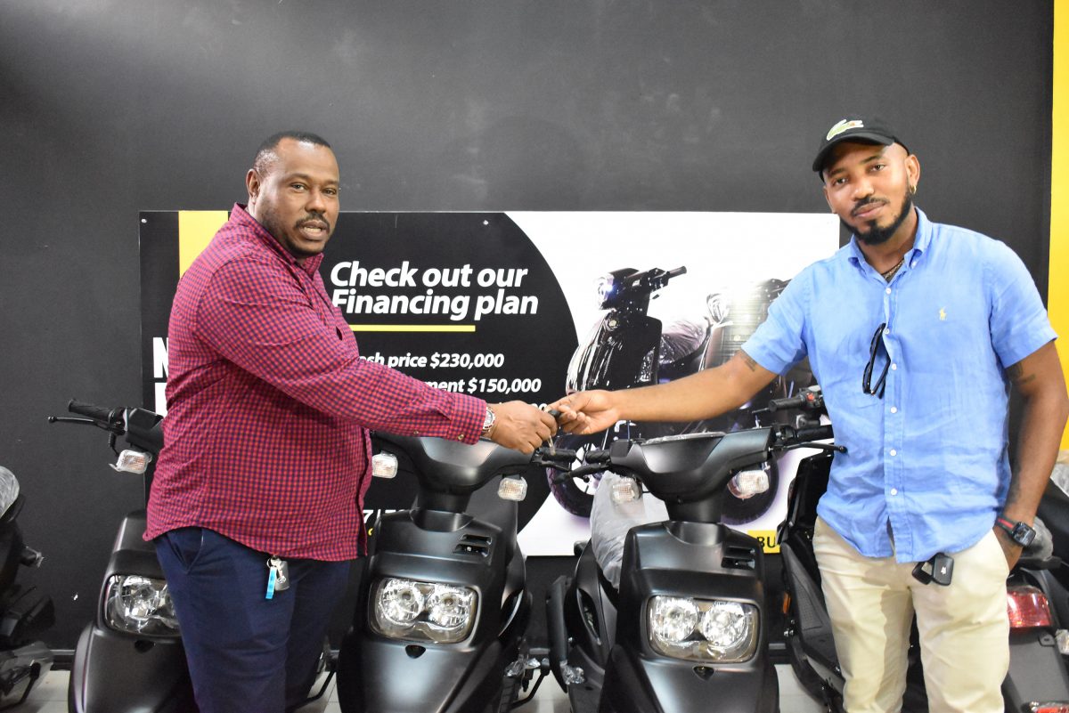 Proprietor of the Luminous Manufacturing and Distribution Eron Baptiste (right) presenting the ignition keys for the two model 1146 (46cc) motorcycles to Co-Director of the Petra Organization Troy Mendonca for the MVP Sports Futsal Championship