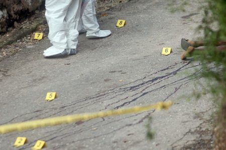 Crime scene investigators collect evidence following the early morning triple murder at Mapp Lands, Laventille, yesterday.