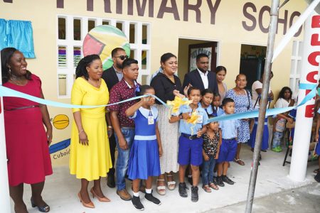 A student and Minister of Education, Priya Manickchand cutting the ribbon to the Swan Primary School 