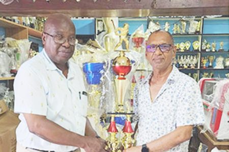 Trophy Stall proprietor, Ramesh Sunich (right), hands over the Legends Over-50 winning trophy to the GSCL president Ian John.