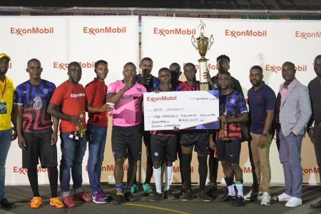 The victorious Unknown unit displaying the championship trophy in the presence of tournament officials and representatives from sponsors at the end of the ExxonMobil Futsal Championship.