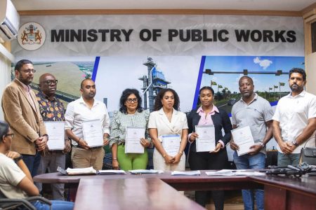 Several of the contract awardees with Permanent Secretary Vladim Persaud (standing at left) at the Public Works Ministry on Friday (Ministry of Public Works photo) 