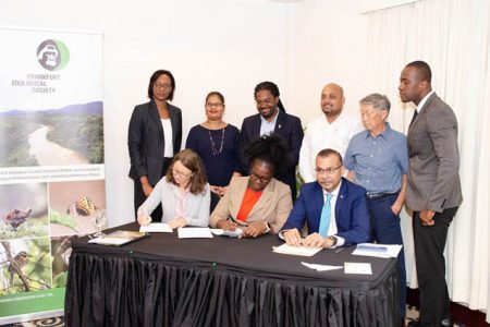 From left Dr. Antje Müllner and Permanent Secretary within the Office of the President, Abeena Moore signing the MoU in the presence of Foreign Secretary Robert Persaud, and other PAC staff (Department of Public Information photo)
