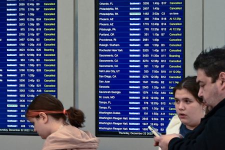 Travelers look over departure notifications as flight cancellations mount as a weather phenomenon known as a bomb cyclone hits the Upper Midwest, at Midway International Airport in Chicago, Illinois, U.S. December 22, 2022.  REUTERS/Matt Marton