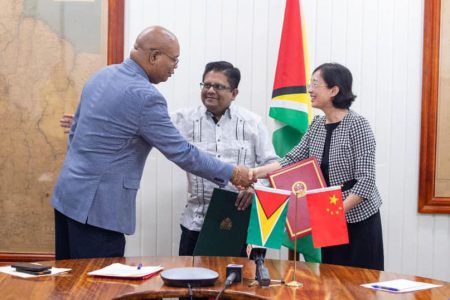 It’s a deal: Minister of Public Works Juan Edghill (left) shaking hands with China’s Ambassador to Guyana, Guo Haiyan. At centre is Minister of Finance, Dr Ashni Singh. (Ministry of Finance photo)
