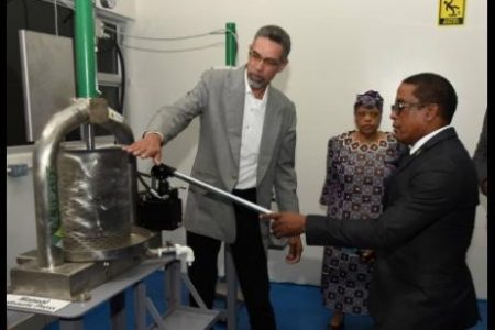 David Harrison (left), director of the Jamaica Business Development Corporation (JBDC), explains the use of the manual hydraulic press to Dr Norman Dunn (right), state minister in the Ministry of Industry, Investment and Commerce, at Friday’s opening of the JBDC essential oils incubator in Kingston. Looking on is Valerie Veira, CEO of the JBDC.