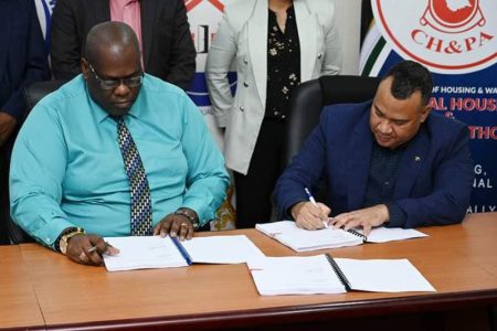 George Melville (right) and Central Housing and Planning Authority (CHPA) CEO Sherwyn Greaves signing the contract (CHPA photo)