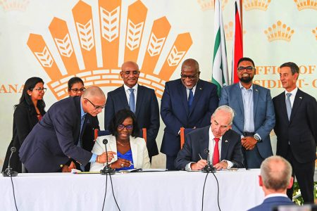 The signing of the pact: John Hess is seated at right and Abena Moore, Permanent Secretary in the Office of the President is seated at left. (Office of the President photo)
