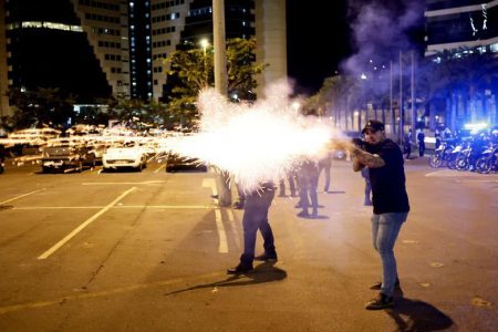 A police officer fires a shotgun as supporters of Brazilian President Jair Bolsonaro protest in Brasilia, Brazil, December 12, 2022. REUTERS/Ueslei Marcelino