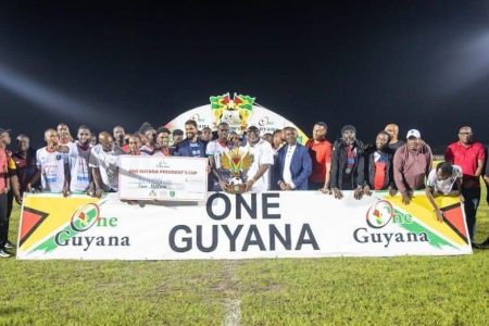 Region #4 captain Daniel Wilson collecting the championship trophy from Prime Minister Mark Phillips in the presence of teammates, Minister of Culture, Youth and Sport, GFF President, and other officials from the tournament

