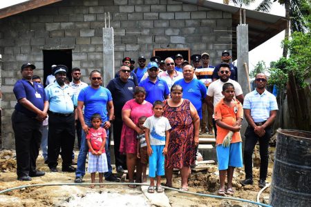 The beneficiary family and members of the Men On Mission at the under construction two-bedroom house. 