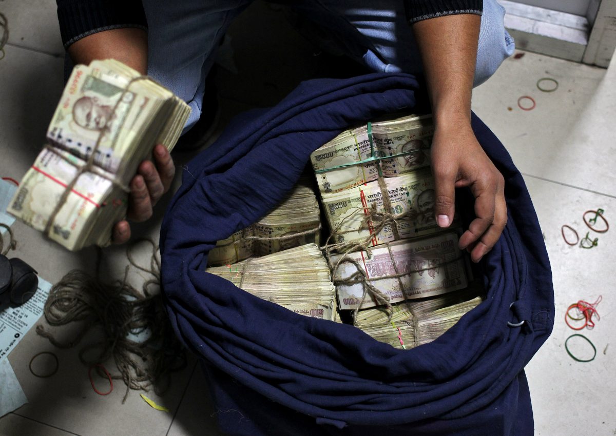 FILE PHOTO: A bank employee takes out a bundle of old 500 Indian rupee banknotes from a sack to count them inside a bank in Jammu, November 25, 2016. REUTERS/Mukesh Gupta