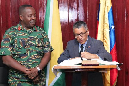 Venezuelan Ambassador to Guyana, Carlos Amador Pèrez Silva signing the visitor’s book.  Chief of Staff (ag) Brigadier Godfrey Bess is at left. (GDF photo)