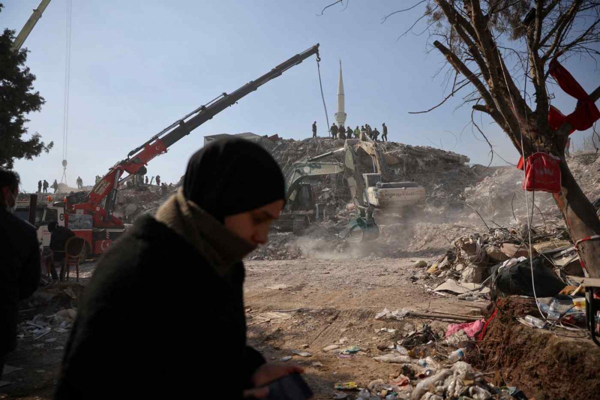 People stand rubble at the site of a collapsed building, as the search for survivors continues in the aftermath of a deadly earthquake in Kahramanmaras, Turkey Feb.12.   © Reuters