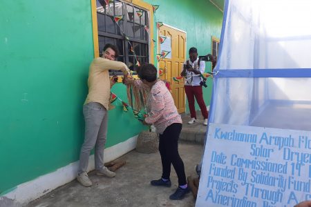 An indigenous ribbon being cut by Resident Representative of the French Embassy in Guyana Pierre Gate and APA Executive Director Jean La Rose to commission the solar dryer compartment 