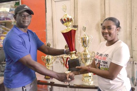 Colin Boyce, Vice President of the Georgetown Dominoes Association
receives one of the trophies from a representative of Trophy Stall.