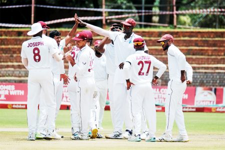 Teammates celebrate with West Indies left-arm spinner Gudakesh Motie (third from left) after he captured one of his seven wickets on the first day of the second Test yesterday at the Queen’s Sports Club in Bulawayo, Zimbabwe. (CWI Media photo)
