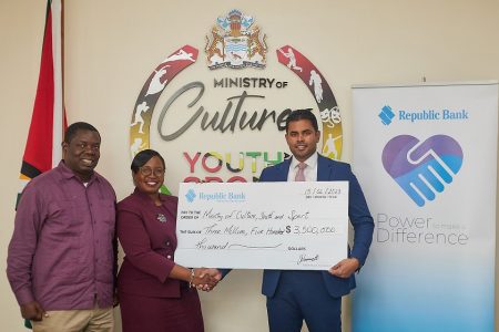 Minister of Culture, Youth and Sport, Charles Ramson (right), receiving the bank’s 2023 sponsorship from Republic Bank (Guyana) Manager of Marketing & Communications, Jonelle Dummett, as Director of National Events, Andrew Tyndall, looks on. (Republic Bank [Guyana]  photo)
