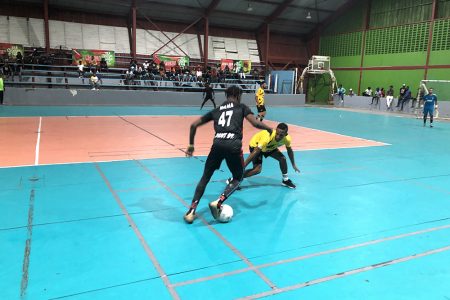 Curtez Kellman (blue) of Sparta Boss in the process of attempting a pass against BV in the Rocks Auto Trans and Spares Parts ‘Legendary Cup’ Futsal Championship
