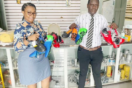 Rondia Lancaster, Office Manager of Devcon Construction and Industrial Supplies and Services alongside club secretary and media officer Calvin Marks displaying the donated football cleats.