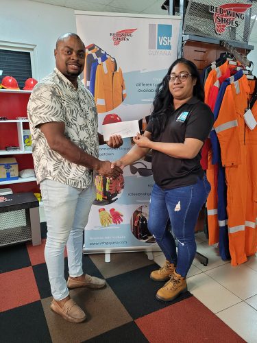 Garment Customisation Lead, Steffanie DeAbreu (right) presenting the sponsorship to Edison Jefford yesterday at the entity’s Carmichael Street Office.