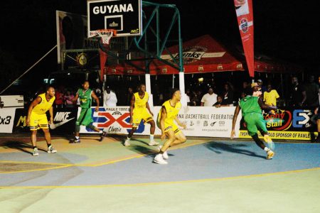 Stanton Rose (green) of Linden All-Stars driving to the basket against Berbice Titans in the Rawle Toney 3x3 Basketball Classic at the Burnham Court