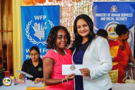 Minister of Human Services and Social Security Vindhya Persaud distributing the WIIN grants to two of the women (Ministry of Human Service photo)