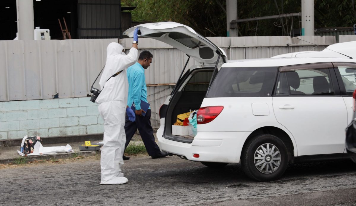 A crime scene Investigator looks into the back of the car in which Natasha Moonasar was shot and killed along the Southern Main Road, Couva, yesterday.