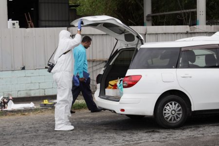 A crime scene Investigator looks into the back of the car in which Natasha Moonasar was shot and killed along the Southern Main Road, Couva, yesterday.