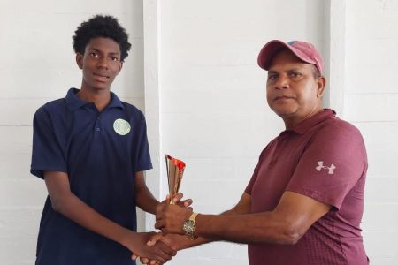 In photo, Jonathan Mentore receives the Man-of-the-Match
trophy from Match Referee, Moses Ramnarine.