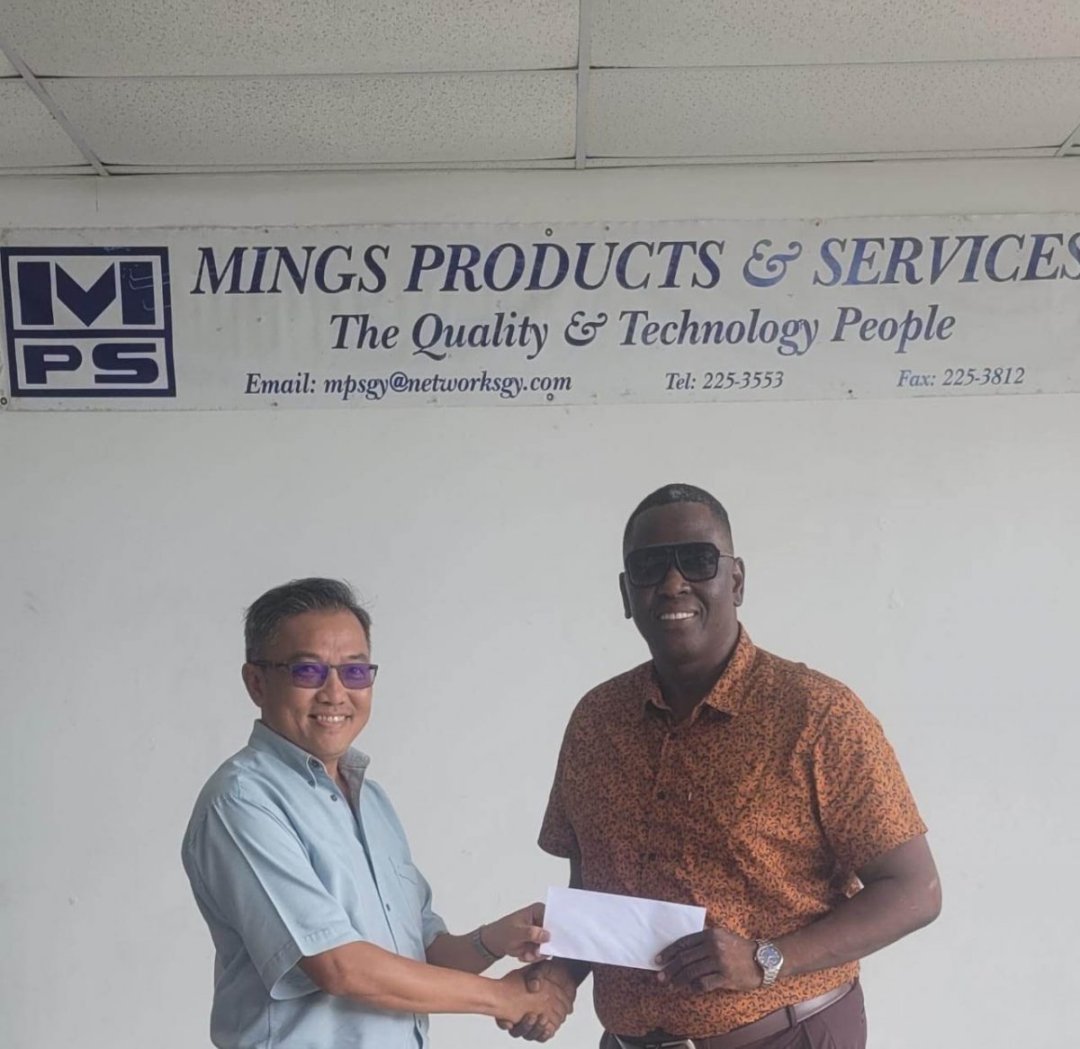 Mings Products and Services Representative, Mr. John Chin hands over cheque to Kenneth Williams.