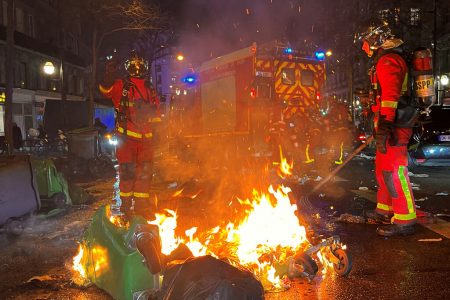 French firefighters extinguish burning garbage bins after a demonstration on the day the National Assembly debates and votes on two motions of no-confidence against the French government for its use of a special clause in the French Constitution, in Paris, France, March 20, 2023 Reuters