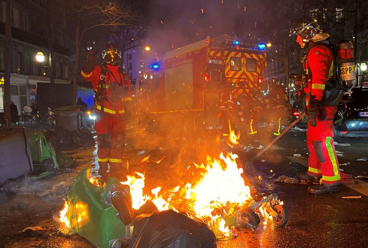 French firefighters extinguish burning garbage bins after a demonstration on the day the National Assembly debates and votes on two motions of no-confidence against the French government for its use of a special clause in the French Constitution, in Paris, France, March 20, 2023 Reuters