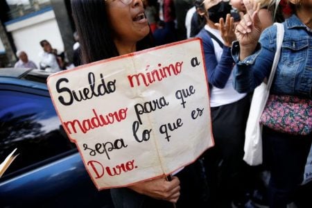 A teacher holds a sign reading "Minimum wage to Maduro to let him know how hard it is" during a protest demanding better salaries in Caracas, Venezuela February 23, 2023. REUTERS/Leonardo Fernandez Viloria