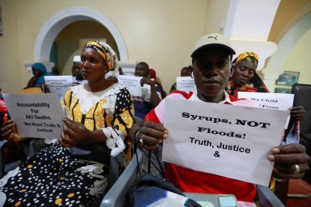 Grieving parents hold up signs during a news conference, calling for justice for the deaths of children linked to contaminated cough syrups, in Serekunda, Gambia, November 4, 2022. REUTERS/Edward McAllister/File Photo
