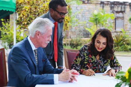  States Ambassador to the Republic of Trinidad and Tobago Candace Bond signs documents for the acquisition of the property at 137 Long Circular Road, Maraval, as the site for the new U.S. Embassy. Looking on are the seller, Joseph Fernandes, and Bernard Shepherd.
