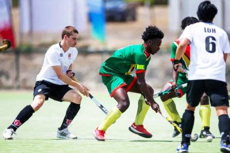 Guyana’s captain Shakeem Fausette attempts
to get past two Canadian defenders
