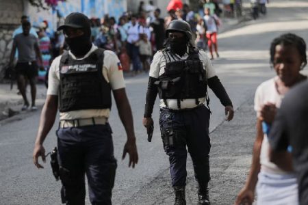 Police officers walk near people who carry their belongings while fleeing their homes and neighbourhood due to clashes between gangs, in Port-au-Prince, Haiti April 24, 2023. REUTERS/Ralph Tedy Erol
