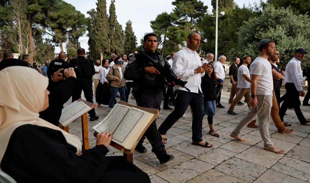 Jewish visitors walk past people reading the Koran, at the compound that houses Al-Aqsa Mosque, known to Muslims as Noble Sanctuary and to Jews as Temple Mount, while tension arises during clashes in Jerusalem’s Old City, April 9, 2023 (Reuters photo)