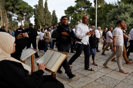 Jewish visitors walk past people reading the Koran, at the compound that houses Al-Aqsa Mosque, known to Muslims as Noble Sanctuary and to Jews as Temple Mount, while tension arises during clashes in Jerusalem's Old City, April 9, 2023 (Reuters photo)