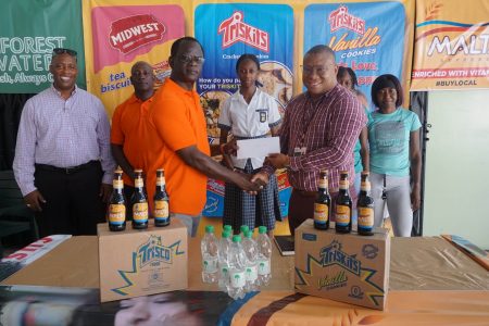 Chief organizer of the Boyce and Associates Relay Festival, Colin Boyce left, receives the sponsorship package from Banks’ Water Beverages Manager, Colin King in the presence of athletes, Coach Mark Scott and Banks’ Outdoor Events Manager, Mortimer Stewart. (Emmerson Campbell photo)