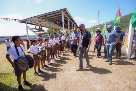 President Irfaan Ali and others being welcomed to the community of Aranaputa Valley, North Rupununi, Region Nine by young musicians (DPI photo)