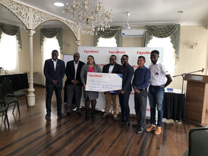 Petra Organization member Nareeza Latiff (3rd from left) receiving the symbolic cheque from ExxonMobil Community Relations Advisor Ryan Hoppie (5th from left) in the presence of GFF Technical Director Bryan Joseph (left), Director of Sport Steve Ninvalle (2nd from left), Petra Co-Director Troy Mendonca (centre), Marti De Souza (6th from left), Deputy Chief Education Officer of the MOE, and Petra Organization member Mark Alleyne